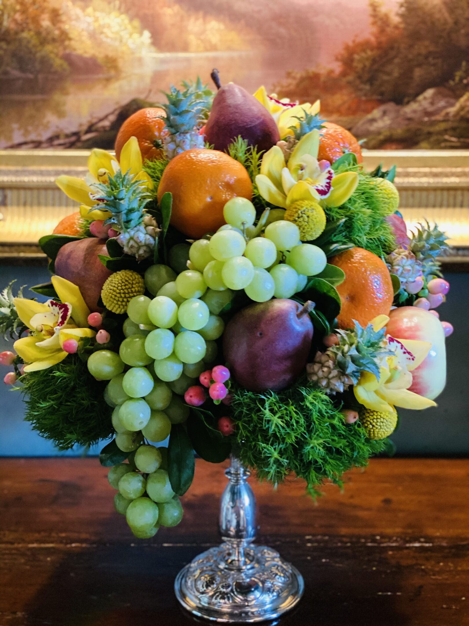 A bouquet of fruit is displayed in front of a painting.