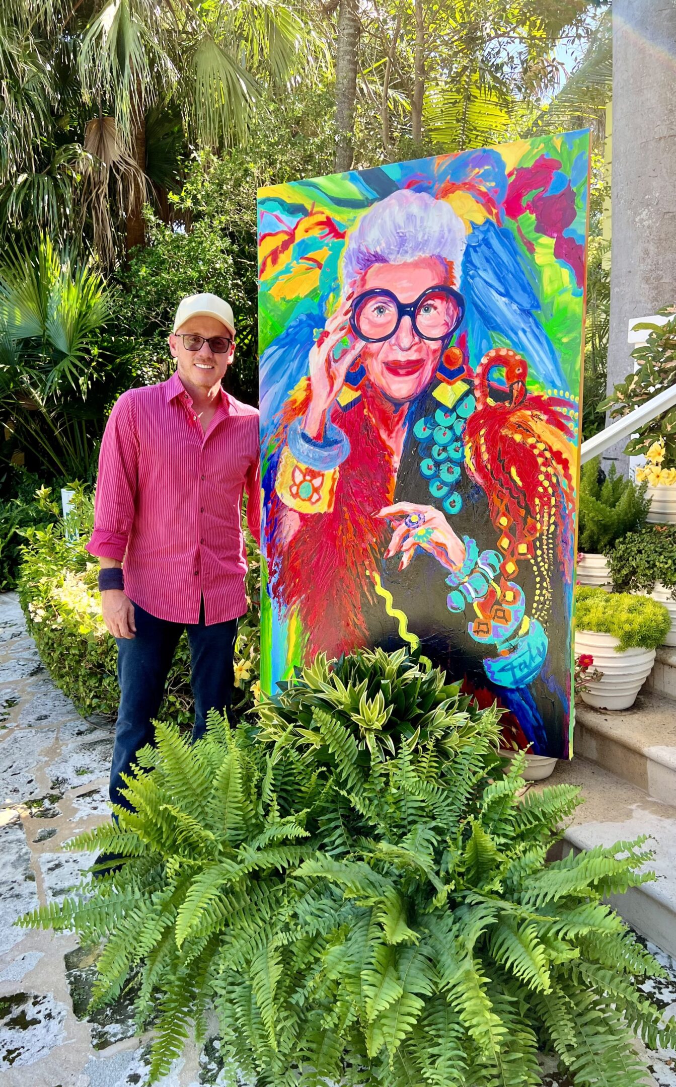 A man standing next to a painting of an older woman.